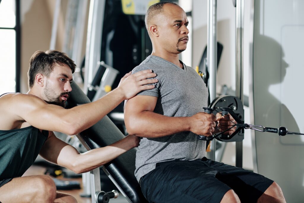 Personal trainer controlling exercising man